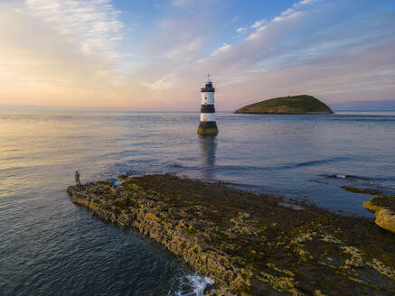 Fisherman at Trwyn Du Lighthouse at sunset in summer, Beaumaris, Wales, Great Britain, United Kingdom, Europe - RHPLF29870