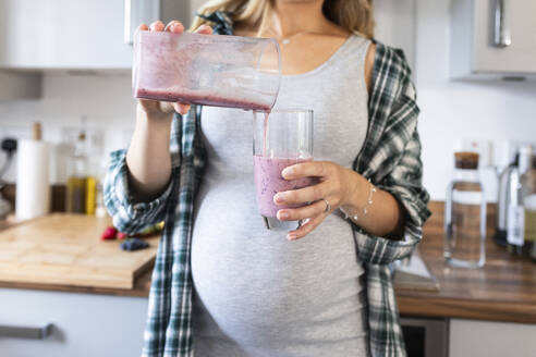 Schwangere Frau gießt Milchshake in Glas - WPEF07859