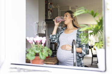 Pregnant woman drinking milkshake seen through window - WPEF07861