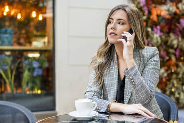 Businesswoman talking on smart phone at sidewalk cafe - DLTSF03676