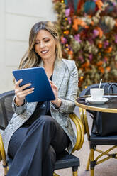 Businesswoman using tablet PC at sidewalk cafe - DLTSF03679