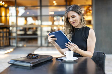 Geschäftsfrau arbeitet an einem Tablet-PC in einem Straßencafé - DLTSF03699