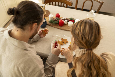 Couple decorating cookies at table in kitchen - VPIF08932