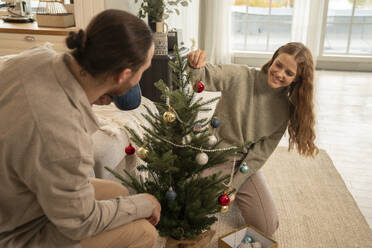 Glückliches Paar beim Schmücken des Weihnachtsbaums zu Hause - VPIF08952