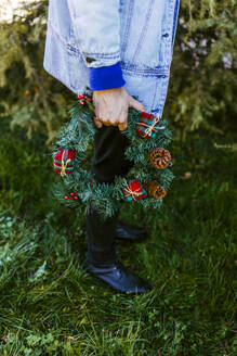 Mann hält Weihnachtskranz und steht auf Gras - EGHF00801