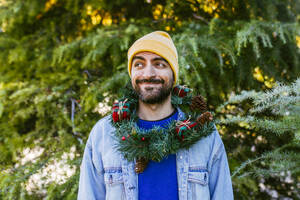 Lächelnder Mann mit Weihnachtskranz um den Hals - EGHF00804