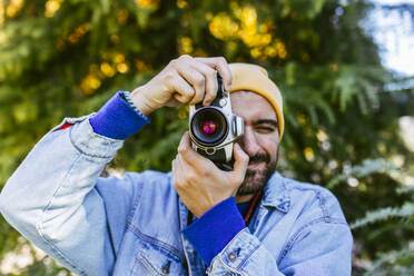 Man photographing through camera in front of tree - EGHF00806