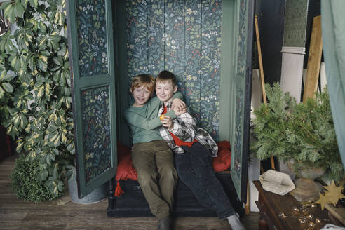 Lächelnde Jungen sitzen zu Hause im Schrank - VBUF00516