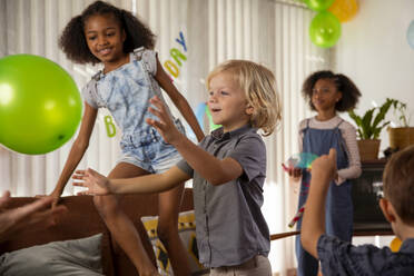 Glückliche Kinder spielen zu Hause mit Luftballons - IKF01427
