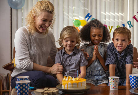 Boy celebrating birthday with mother and friends at home - IKF01435