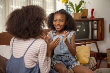 Girls playing clapping game at home - IKF01444