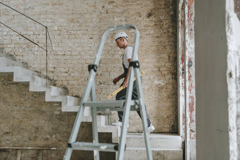 Bauingenieur, der die Treppe auf der Baustelle hinaufgeht - YTF01462