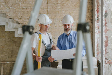 Happy architect having discussion with building contractor at site - YTF01463
