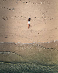 Aerial view of a woman relaxing on the beach along the shoreline in Ilot Lievres, Trou d'Eau Douce, Flacq district, Mauritius. - AAEF24623