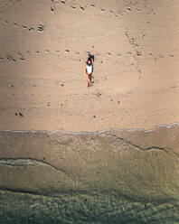 Luftaufnahme einer Frau, die sich am Strand entlang der Küste in Ilot Lievres, Trou d'Eau Douce, Bezirk Flacq, Mauritius, entspannt. - AAEF24623