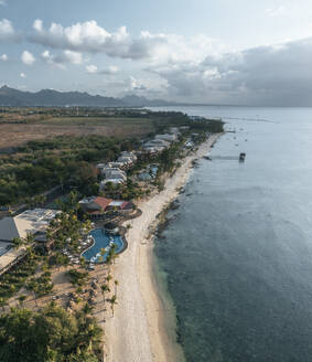 Aerial view of hotels and resorts on the beachfront along the coastline facing the ocean at sunset in Pointe aux Piments, Pamplemousses, Mauritius. - AAEF24630