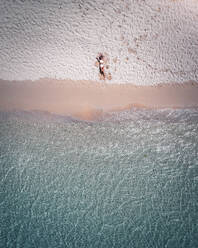 Aerial view of a woman relaxing on Pomponette Public beach along the shoreline, Chemin Grenier, Savanne District, Mauritius. - AAEF24651
