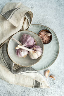 Top view of raw garlic heads in the bowl as a cooking ingredient on concrete background - ADSF49521