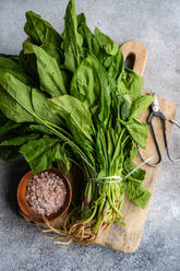 Top view of bunch of fresh spinach leaves on rustic wooden board accompanied by aromatic spices in bowl symbolizing healthy salad preparation - ADSF49523