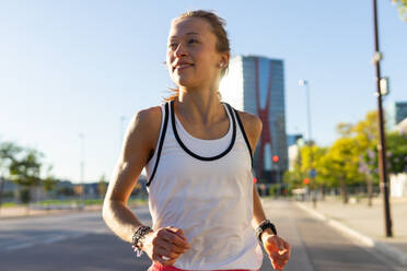 Photo of a woman running down a sidewalk in a city. Active Lifestyle in the Urban Jungle - ADSF49574