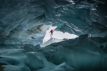 Unrecognizable skier with ski poles walking in cave at snowy mountain while exploring during vacation at Swiss Alps - ADSF49635