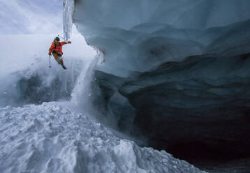 Full body of anonymous person skiing on snowy mountain on winter day during vacation seen through cave at Swiss Alps - ADSF49636