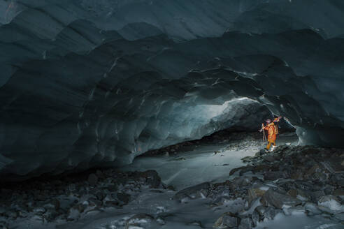 Side view of unrecognizable skier with ski poles walking in cave at snowy mountain while exploring during vacation at Swiss Alps - ADSF49638