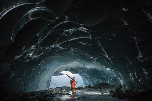 Side view of skier with ski poles walking in cave at snowy mountain while exploring during vacation at Swiss Alps - ADSF49639