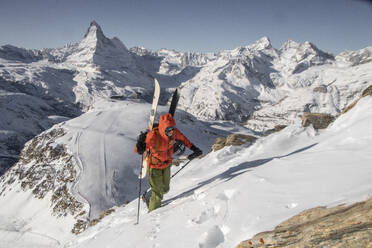 From above of anonymous person climbing on snow covered mountain slope against clear blue sky at Swiss Alps - ADSF49654