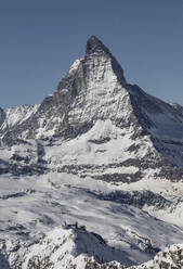 Scenic view of mountain range with rocks covered in snow under clear blue sky on sunny day in winter season - ADSF49660