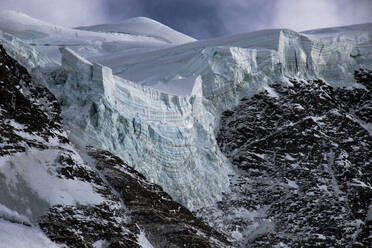 Close up view of a glacier edge with textured ice layers, contrasting against rugged mountain terrain - ADSF49668