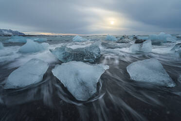 Picturesque scenery of rippling sea water with pieces of broken ice floating against cloudy sky in Diamond Beach in Iceland - ADSF49687