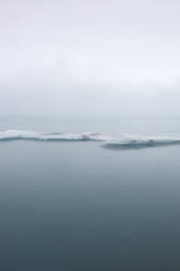 View of ice formation surrounded with calm and scenic sea water against sky in winter at Iceland - ADSF49704