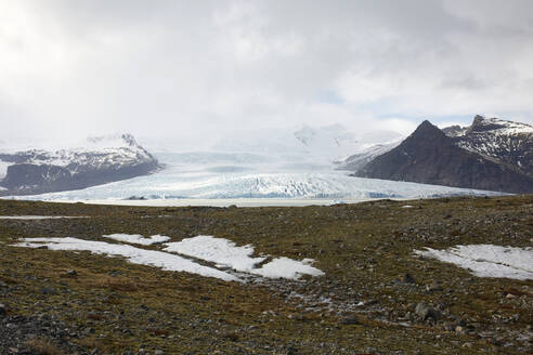 A vast glacier nestled between rugged mountains under a cloudy sky in Iceland - ADSF49707