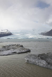 Picturesque view of glacier and frozen lake with snowy mountains against sky during winter at Iceland - ADSF49708