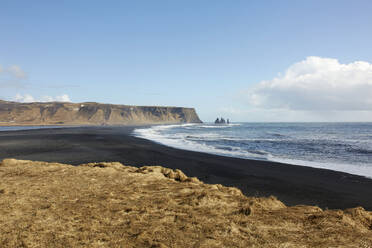 Picturesque view of ocean with tranquil beach and coastline by cliff against cloudy sky in Iceland - ADSF49710