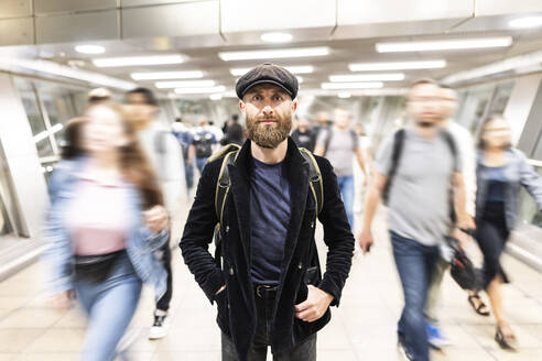 Älterer Mann steht inmitten von Menschen, die sich in einer U-Bahn-Station bewegen - WPEF07872