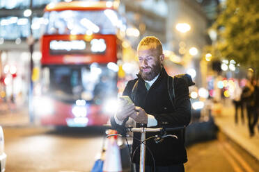 Mature man surfing net through smart phone in city at night - WPEF07884