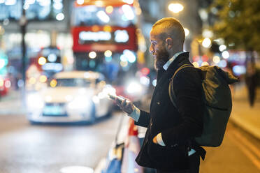 Mann mit Hand in der Tasche benutzt Smartphone in der Stadt - WPEF07890