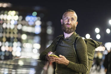 Mature man holding mobile phone at night - WPEF07901