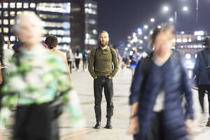 Älterer Mann steht mit den Händen in den Taschen auf dem Gehweg - WPEF07906