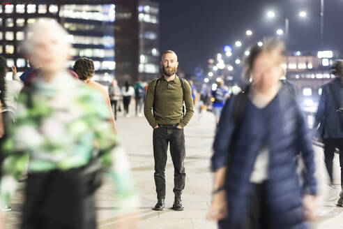 Mature man standing with hands in pockets on footpath - WPEF07906