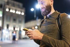 Älterer Mann mit Bart benutzt Handy in der Stadt bei Nacht - WPEF07917