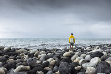 Man standing on rocks in front of sea under sky - WVF02047