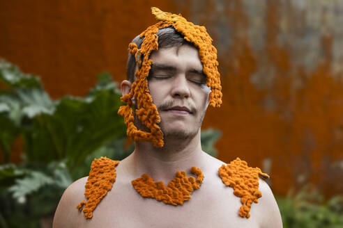 Mann mit geschlossenen Augen, bedeckt mit orangefarbenem Moos - WVF02049