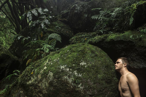 Mann ohne Hemd steht in der Nähe von Felsen im Regenwald - WVF02073