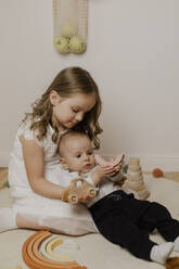 Liebevolle Schwester und Bruder spielen mit Spielzeugblöcken im Wohnzimmer zu Hause - EHAF00147