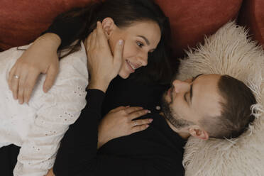 Young man lying down and embracing woman at home - EHAF00154