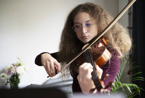 Mädchen mit krausem Haar spielt Geige zu Hause - NJAF00686