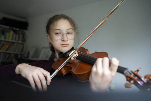 Girl wearing eyeglasses and playing violin at home - NJAF00691